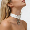Close-up of a woman wearing a white choker with a heart-shaped pendant on a plain background